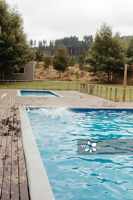 乡村环境中带有水花和美丽自然景观的游泳池区域，阴天。图片素材