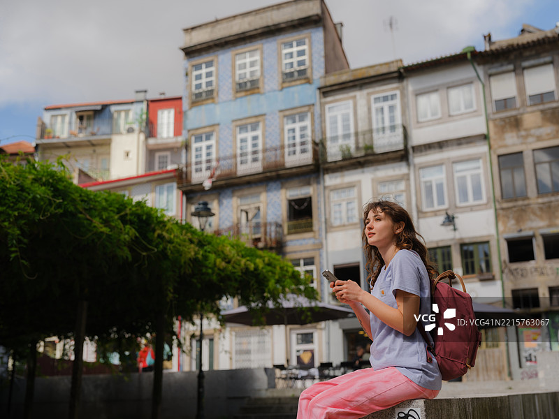 在葡萄牙波尔图走路时使用智能手机的女性图片素材