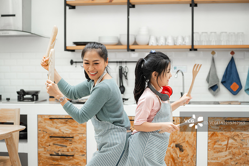 快乐的家庭在厨房里一边准备食物一边跳舞，享受乐趣图片素材