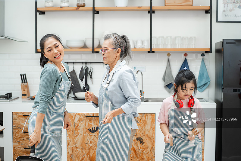 快乐的家庭在厨房里一边准备食物一边跳舞，享受乐趣图片素材