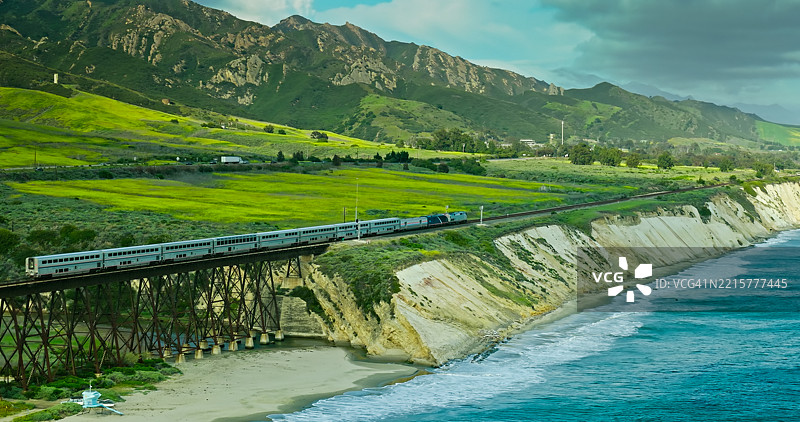乘客列车在绿色山丘和太平洋海岸线的航拍照片图片素材