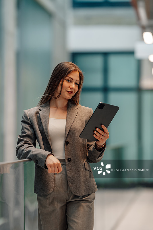 年轻女商人在现代办公大楼中使用数字平板电脑图片素材