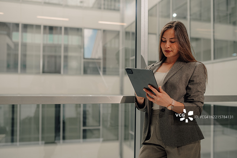 商务女性在现代办公大楼中使用数字平板电脑图片素材
