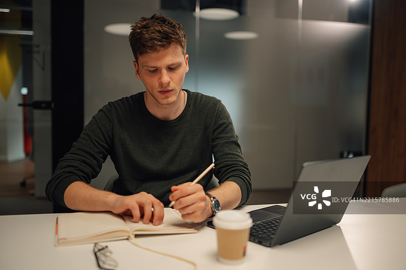 专注的商人在深夜工作时做笔记图片素材