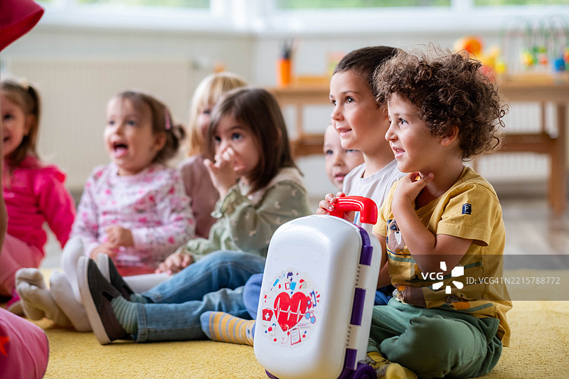 快乐的孩子们坐在幼儿园的地板上玩耍图片素材