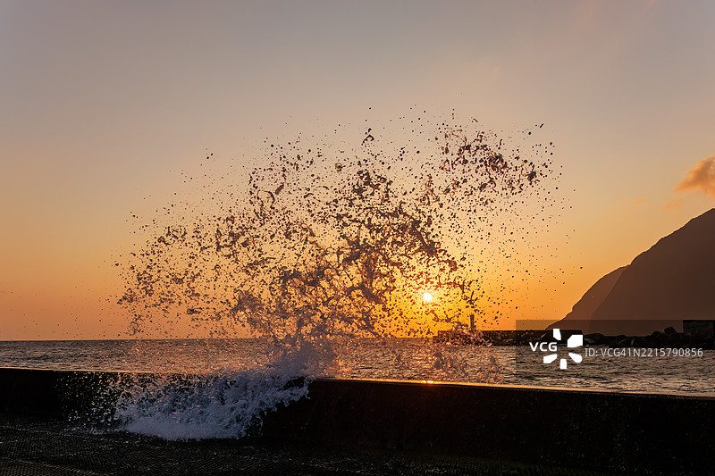 太平洋的汹涌波涛沐浴在八丈岛的晨光中。清晨时分，底港和底港海滩的日出。图片素材