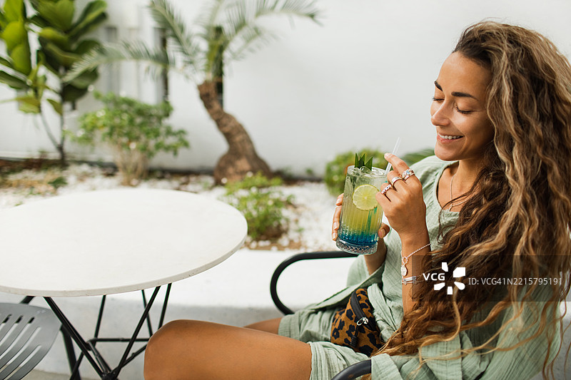 女人在放松的户外环境中享受新鲜的热带鸡尾酒图片素材