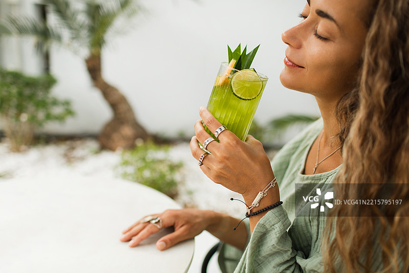 女人在阳光明媚的日子里享受清爽的绿色饮品图片素材