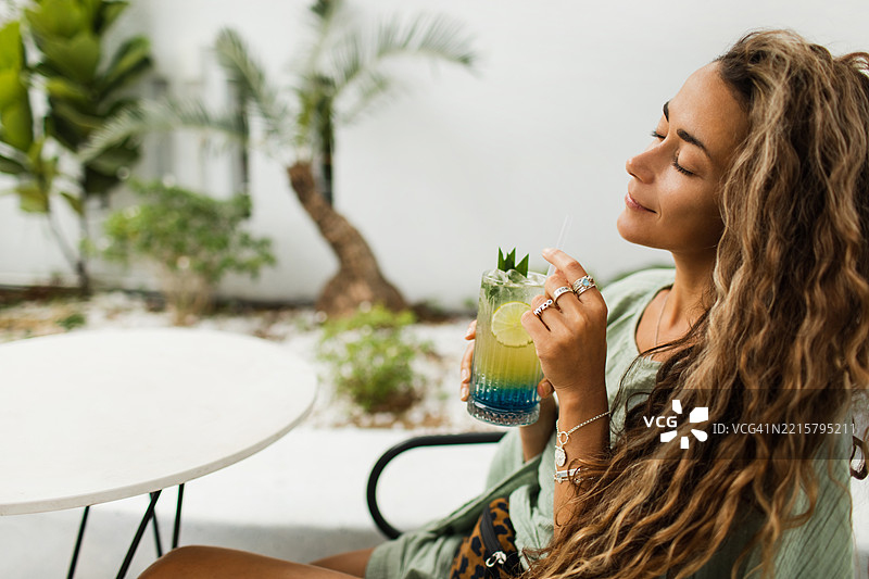女性在放松的户外环境中享用新鲜的热带鸡尾酒图片素材