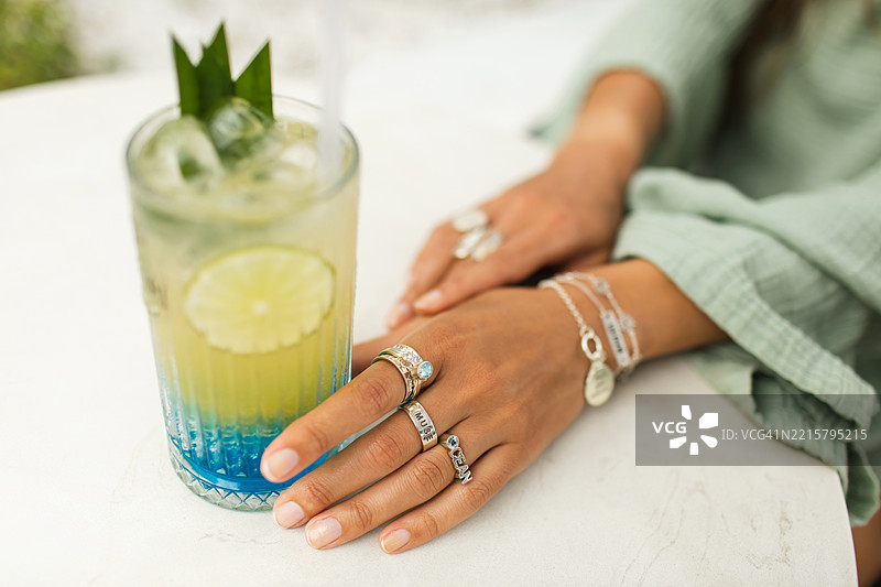 时尚女性在阳光明媚的日子里享用冰镇柑橘饮品，佩戴优雅的珠宝图片素材