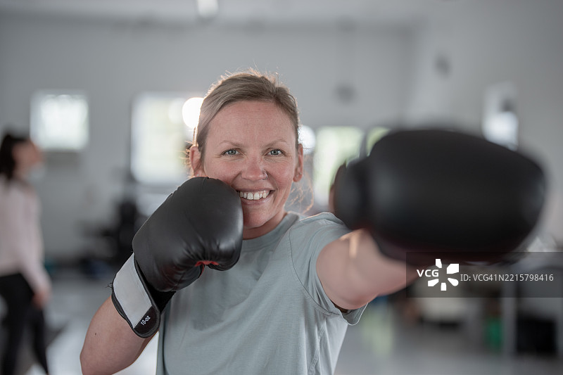 微笑的女性在拳击课上练习自卫技巧图片素材
