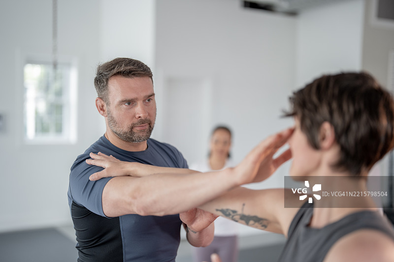 男性教练在课堂上教授女性自卫技巧图片素材