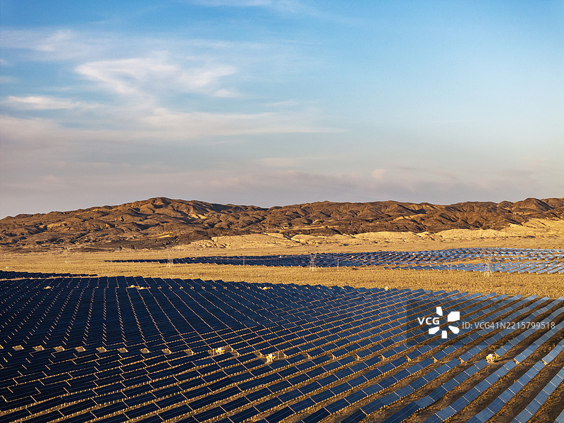 戈壁沙漠中整齐排列的太阳能电池板的鸟瞰图。图片素材
