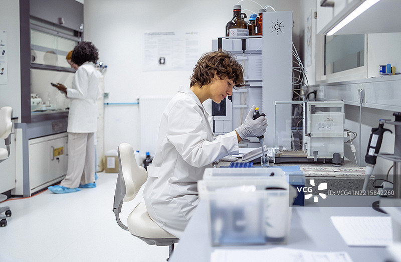 中年女性科学家穿着实验室外套在现代实验室环境中分析样本图片素材