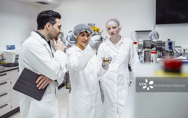实验室技术人员穿着白大褂在现代制药设施中讨论质量控制结果图片素材