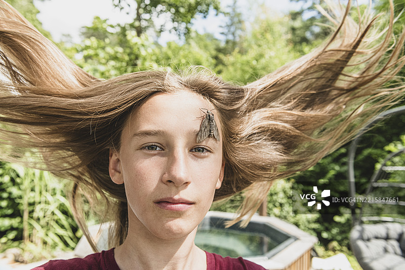 女孩的肖像，蓬乱的头发上坐着一只鹰蛾。图片素材