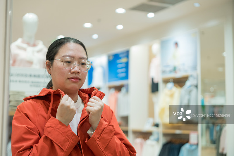 一位亚洲母亲正在商场与她的宝宝一起购物；挑选衣服图片素材