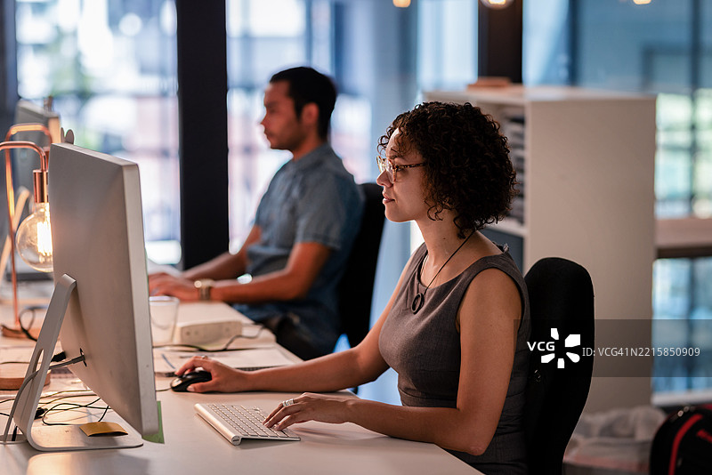 专业人士在现代办公桌前使用电脑，在舒适的灯光下专注协作图片素材