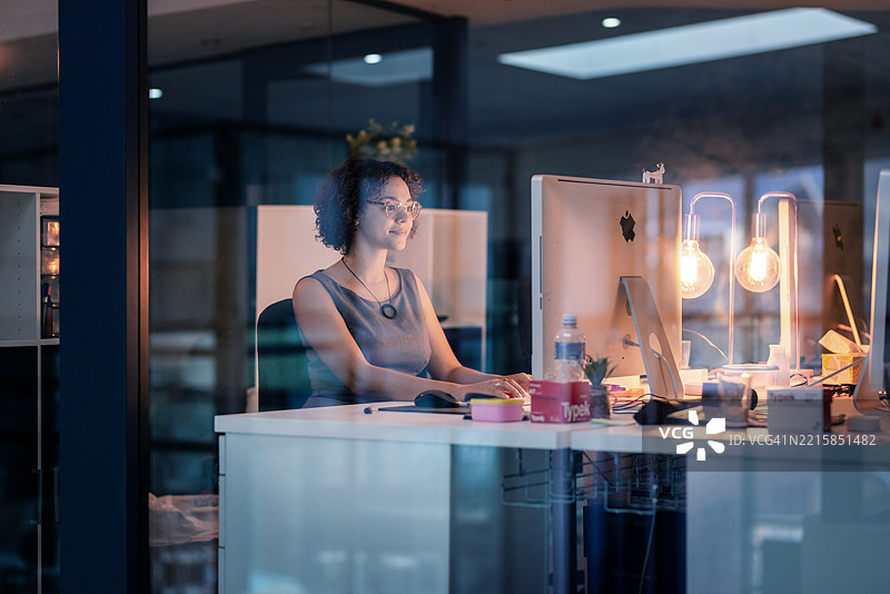 年轻专业人士在现代办公室桌前加班图片素材