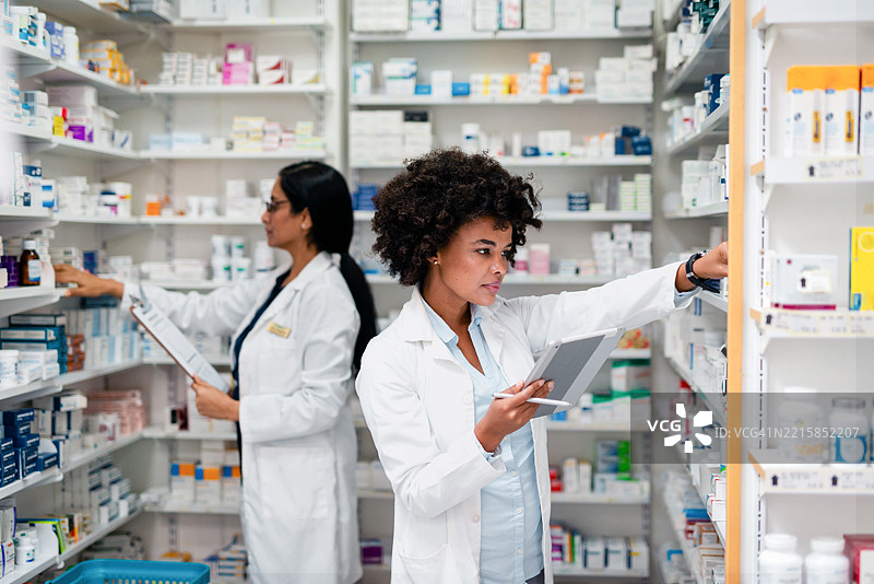 药剂师在药店环境中整理药物以满足处方需求图片素材
