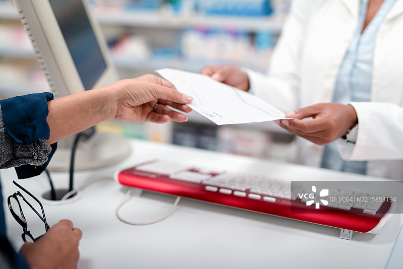顾客在现代药店中从药剂师那里领取处方药图片素材