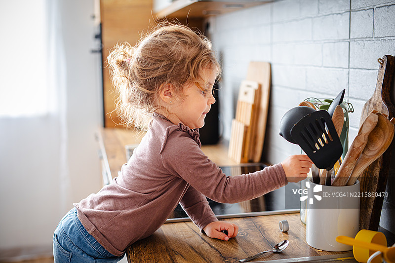 可爱的小女孩试图够到厨房用具图片素材