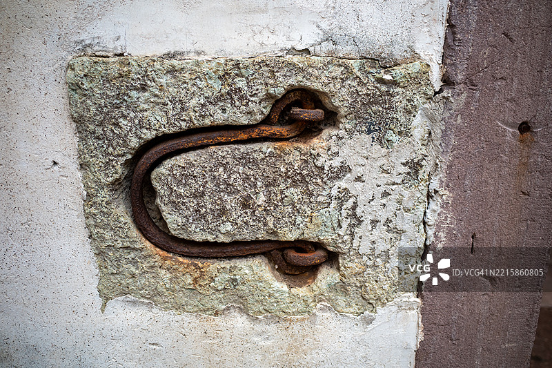 锈迹斑斑的金属钩子嵌入在风化的墙壁上的木门上图片素材