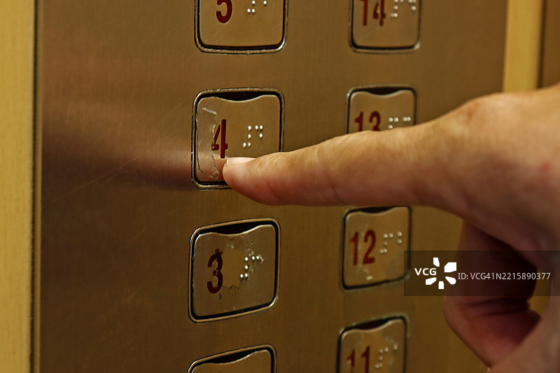 手指按下施耐德电梯面板上的数字四按钮图片素材
