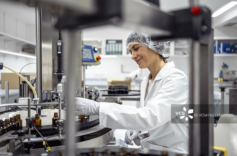 中年女性实验室工作人员在现代实验室环境中包装瓶子图片素材