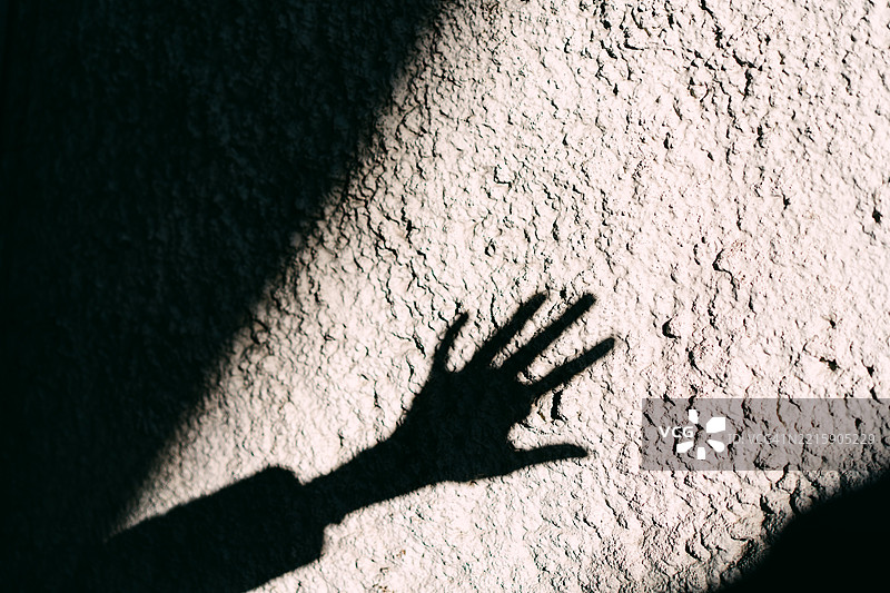 手的影子投射在有纹理的墙面上图片素材