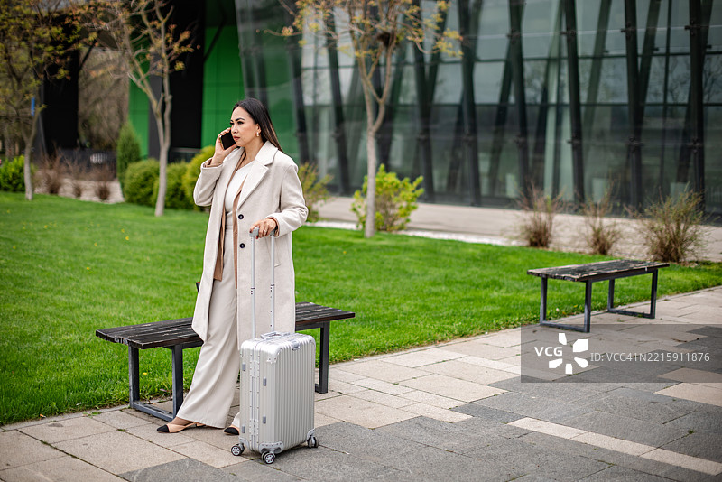 白天在城市户外空间打电话的女商人和行李图片素材
