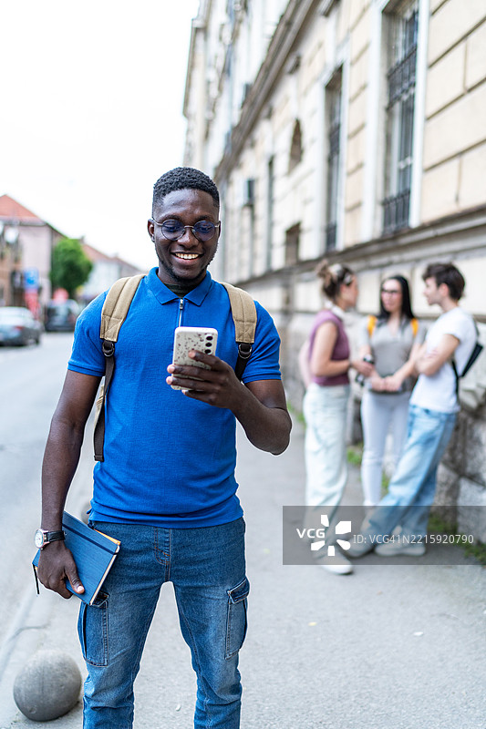 年轻人在城市街道上使用智能手机图片素材