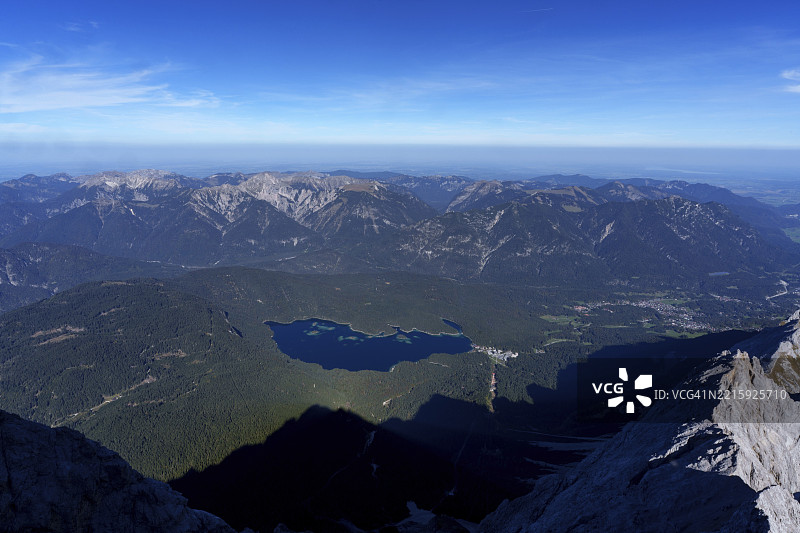 广阔的视野俯瞰着一座山湖和树木环绕的山丘，天空晴朗，位于奥地利蒂罗尔州的厄尔瓦尔德，祖格峰。图片素材