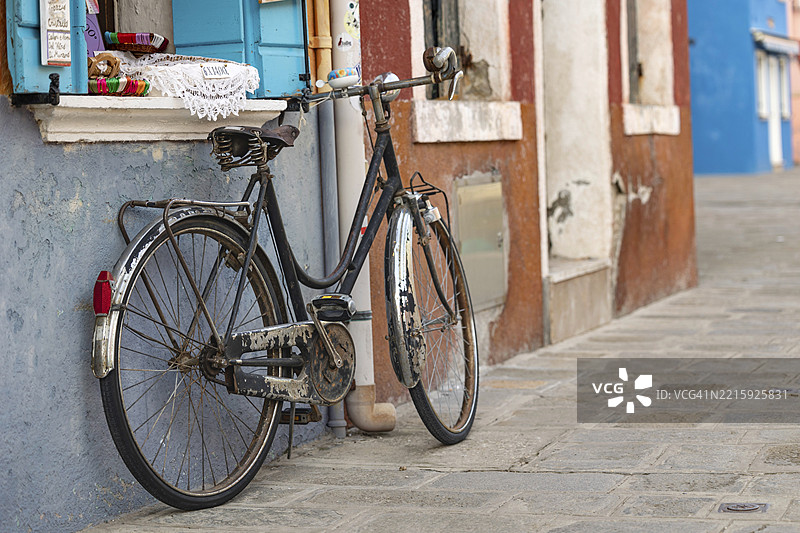 一辆旧自行车靠在色彩斑斓的房屋外立面上,背景是鹅卵石,象征性的图像,布拉诺岛,威尼斯,威尼托地区,意大利,欧洲图片素材