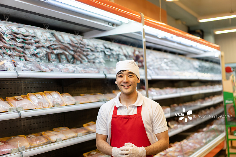 面包师傅站在面包店的货架旁，周围是各种烘焙产品的肖像图片素材