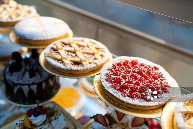新鲜出炉的蛋糕和派整齐地摆放在面包店的展示柜中图片素材