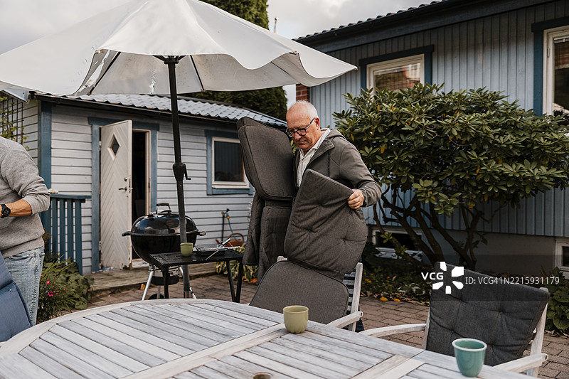 老年男子在后院的桌子上组装椅子罩。图片素材