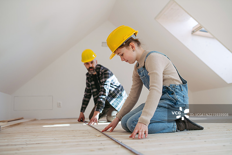 父亲和女儿正在测量房间的长度和宽度，进行家庭装修。图片素材