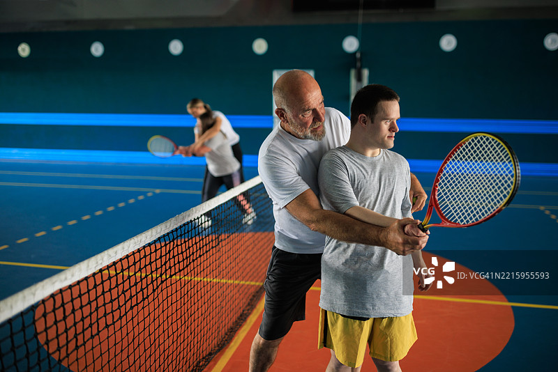 网球教练与唐氏综合症运动员合作图片素材