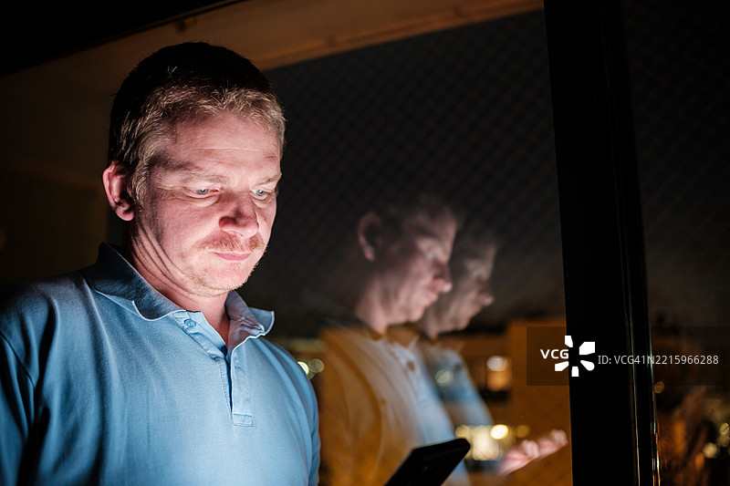 男人在窗边夜间使用智能手机图片素材