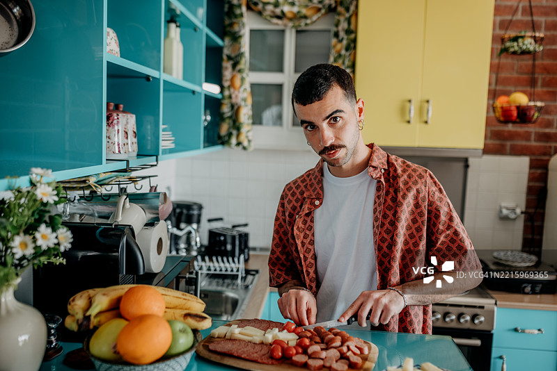 穿着休闲的男子在家中准备食物时为相机摆姿势图片素材