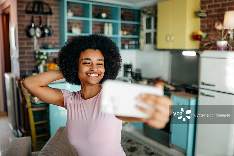 微笑的年轻美女在家里的沙发上放松时自拍图片素材