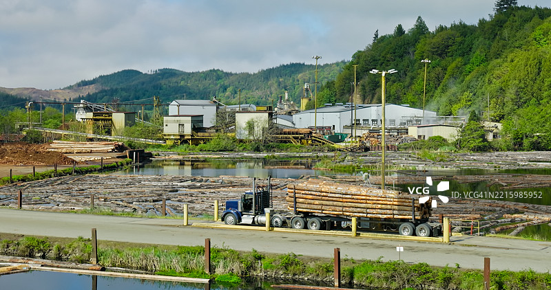 装载货物的卡车经过俄勒冈州科基尔的伐木池图片素材