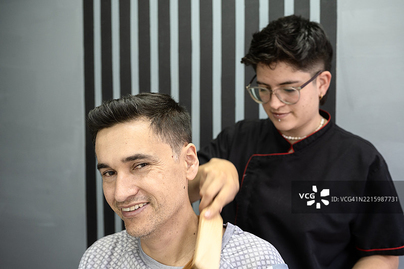 理发师在理发店为顾客剪发后刷颈部图片素材