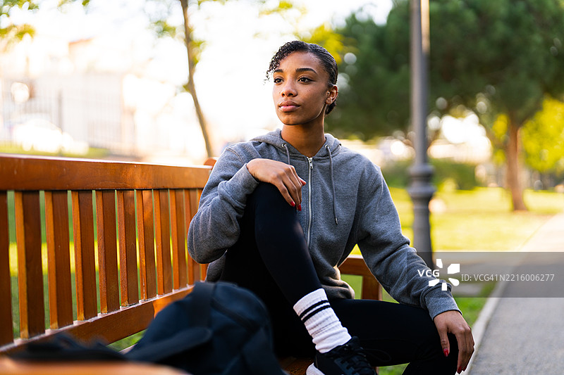 年轻的运动女性在公园的长椅上放松，训练后休息。图片素材