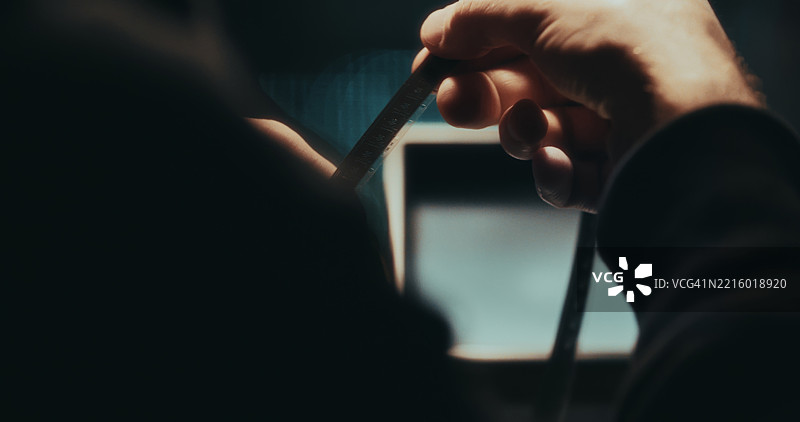 一只手小心翼翼地将16毫米胶卷穿过手动编辑设备。图片素材