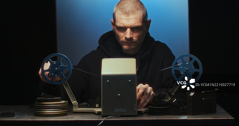 一位导演在复古的模拟剪辑台上工作，使用双卷轴和16毫米胶卷。图片素材