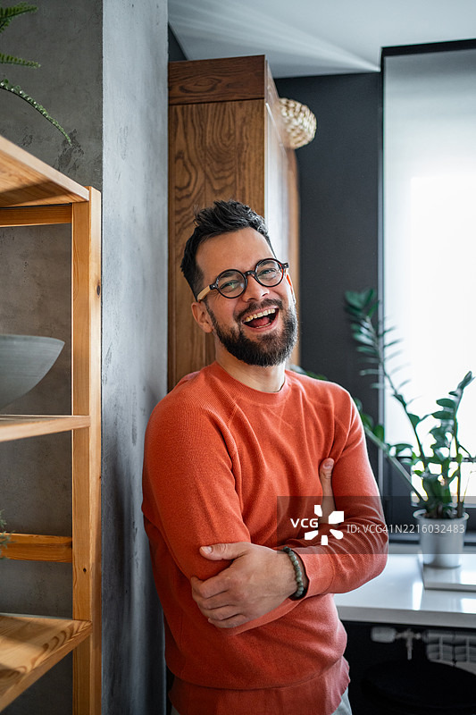 年轻男子靠在墙上，微笑着戴着眼镜图片素材