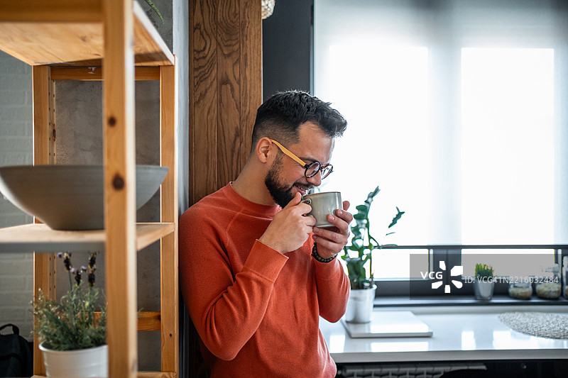 年轻男子在现代厨房中享受一杯咖啡图片素材