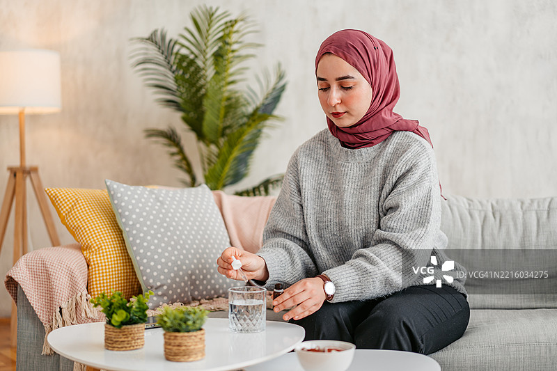年轻穆斯林女性在玻璃杯中滴入药水图片素材